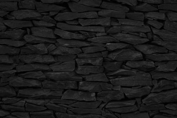 Old dark black stone brick wall texture with vintage style for background and design art work.