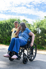 Grandmother in a wheelchair giving a kiss on the hand to her 8-year-old grandson