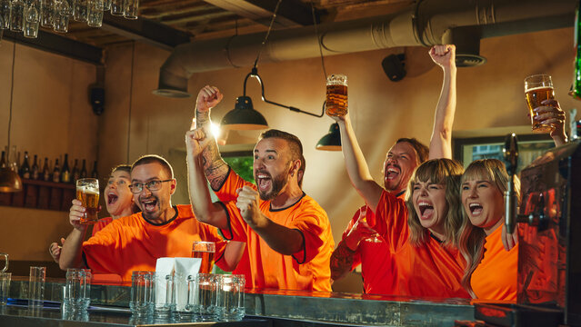Happy young men and women, football enthusiasts celebrate at bar, raising their beers and cheering, victory of favorite sport team. Concept of friendship, soccer fan, championship, support. Ad