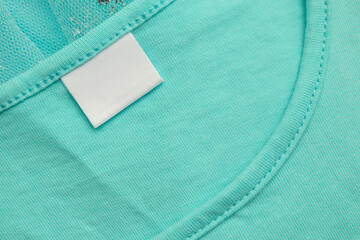 White blank laundry care clothes label on blue shirt fabric background