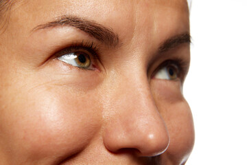 Fototapeta premium Detailed photo of woman's face, preorbital zone with well-kept, smooth skin against white studio background. Anti-aging skincare cosmetic products. Concept of facial care, lifting, spa procedures.