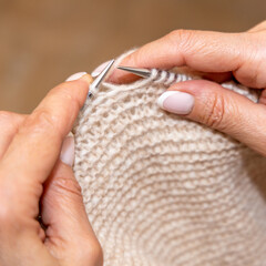 Obraz premium Close up of hands of unrecognizable woman knitting handmade clothes with spokes using wool yarn. Concept of leisure activity.Knitting from yarn on coarse spokes.
