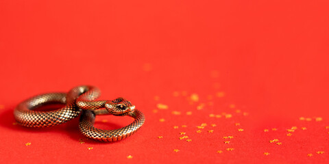 Bronze snake figurine on a red background. The symbol of 2025.