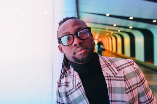 Businessman in checked blazer leaning on illuminated wall