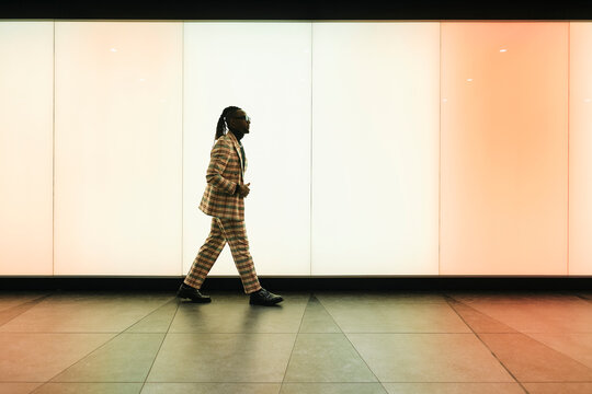 Businessman walking across illuminated wall