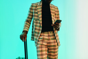 Businessman in checked suit using smart phone near illuminated wall