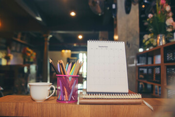 Agenda, planner book, calendar, pencil, and cup of coffee place on business office desk. Diary for organizer to plan timetable, daily appointment, and management job at room. Planner concept