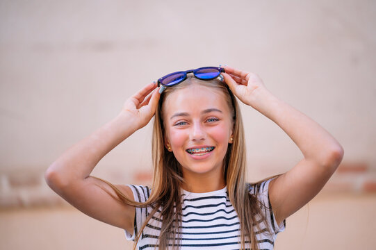 Blond hair girl with braces holding sunglasses