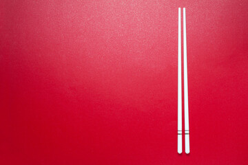 Top view of white ceramic chopsticks on red background