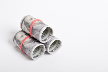 Dollar roll wrapped with red rubber. 100 dollar bills on a roll isolated on white background. Rolled American dollars banknotes