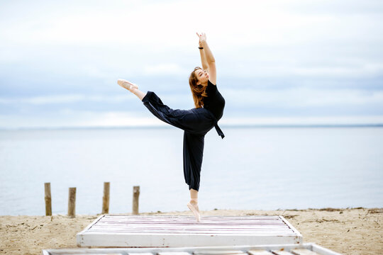 Young woman in arabesque position standing near lake