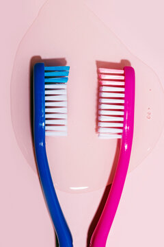 Toothbrushes with water spilled on pink background