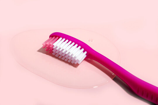 Toothbrush kept on spilled water over pink background