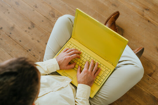 Businesswoman using yellow laptop siting on floor
