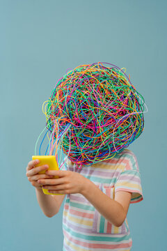 Girl with chaotic thoughts using smart phone against blue background