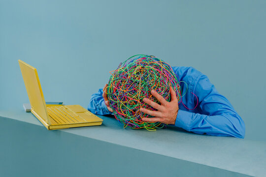 Frustrated businessman with mask of chaotic thoughts against blue background