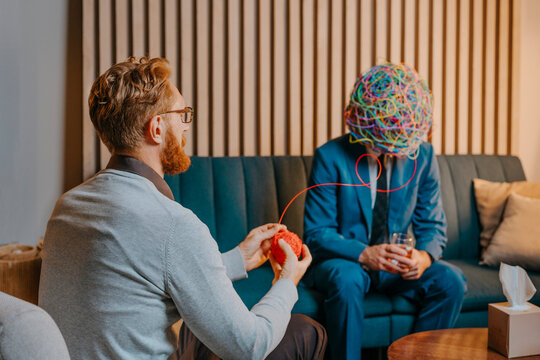Psychotherapist untangling wire from chaotic mask of patient sitting on sofa