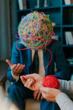 Psychotherapist's hand untangling wire from mask of chaos