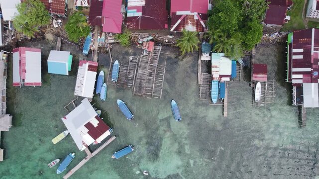 Aerial birds eye view of colorful boats docked along the shoreline of Bastimentos Island in Bocas del Toro District, Panama.