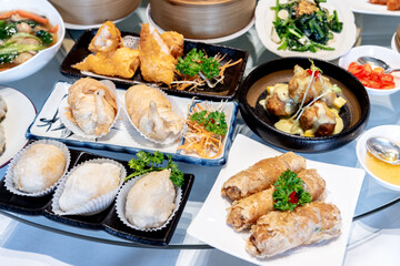Image of various Chinese dim sum in a bamboo steamer, equipped with chopsticks and tea, on a wooden table. 