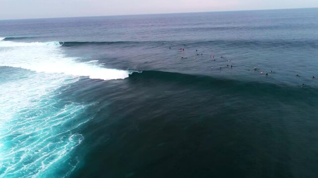 Drone pans above barreling wave and surfers at Cloudbreak Fiji