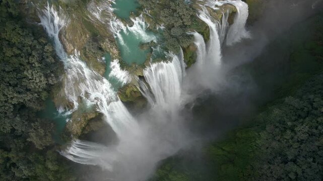 Drone orbit ascend above Tamul waterfall, grand colorssal water cascading into canyon
