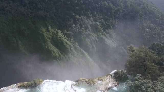 Drone dolly as mist flies into air from crashing water flowing from Tamul Waterfall, Mexico