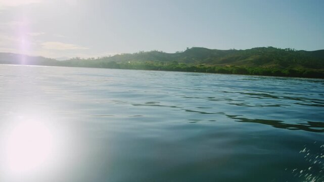 Sparkling shimmering light of sun across dreamy ocean water with tropical background