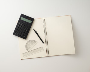 Collective image of stationery.
Notebook, protractor, ruler, calculator and pen.