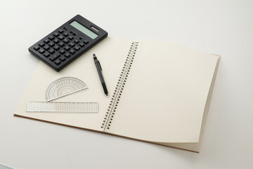 Collective image of stationery.
Notebook, protractor, ruler, calculator and pen.