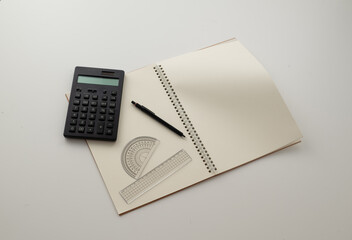 Collective image of stationery.
Notebook, protractor, ruler, calculator and pen.