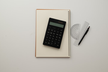 Collective image of stationery.
Notebook, protractor, ruler, calculator and pen.