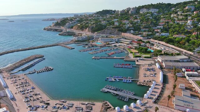 Marseille, France: Aerial view of Marina Olympique, main marina for Olympic Summer Games Paris 2024, flags of participating states flutter in wind - landscape panorama of Europe from above
