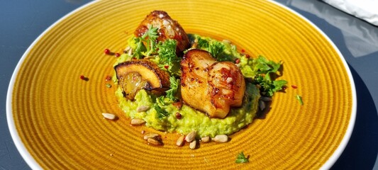 Fresh norwegian scallop on a yellow plate in summer sunshine in resturant in northern Norway