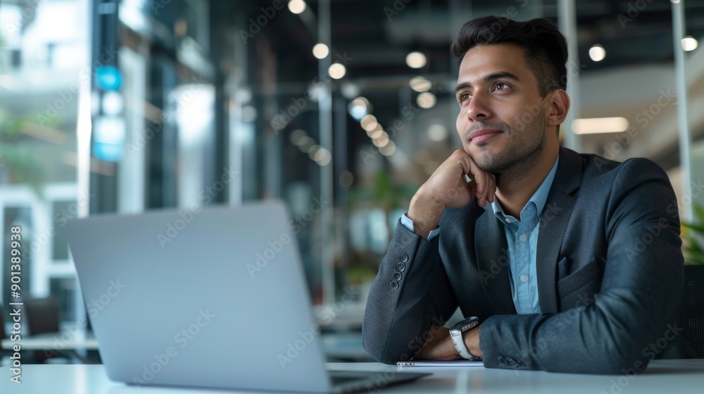 Poster a man in a suit is sitting at a desk with a laptop open in front of him