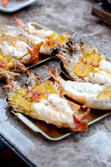 Grilled giant river prawn in a Thai luxury restaurant. Seafood in Thailand. Grilled giant river prawn served on a plate with Thai seafood sauce. Thai cuisine. Grilled giant shrimp on a dinner table.