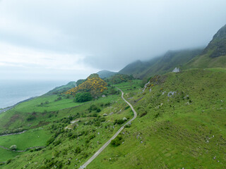 Hügelige Landschaft an der Küste von Nordirland mit einsamer Straße die in die Berge führt