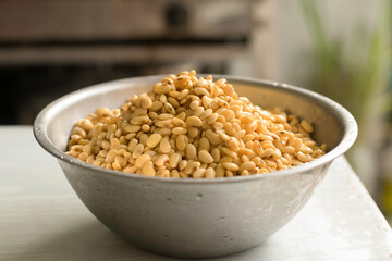 A big bowl of soaked soybean isolated on white table in kitchen selective focus blur background closed up. Prepare to make soymilk (soybean milk or hoya milk)