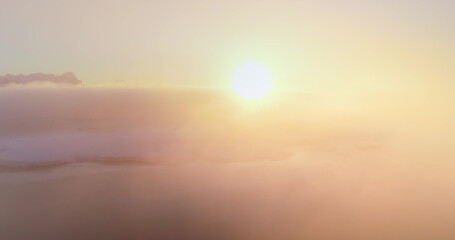Colorful sunrise over Antarctica ocean coast. Aerial drone flight above telecom engineer maintenance cell signal antenna from polar base station. Morning orange bright fog background. Nature wallpaper