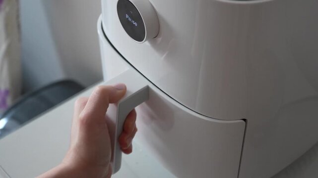 A close-up view of an air fryer drawer being opened to reveal freshly baked bread rolls inside, showcasing the convenient and healthy cooking method