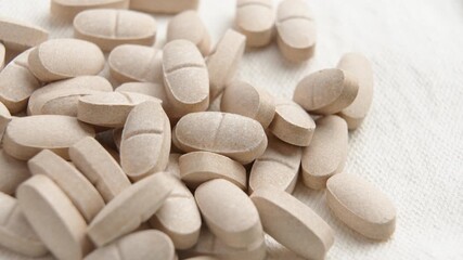 Natural supplements for enhanced vitality and wellness. Alternative medicine pills on a beige cloth. Macro shot. Rotation