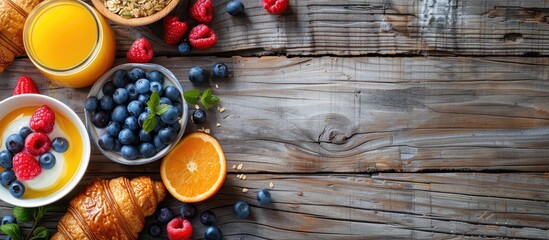 French breakfast staples like yogurt berries orange juice muesli and croissants beautifully displayed on a rustic wooden table with ample copy space image