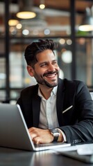 Fototapeta premium A man in a suit is smiling and sitting at a desk with a laptop