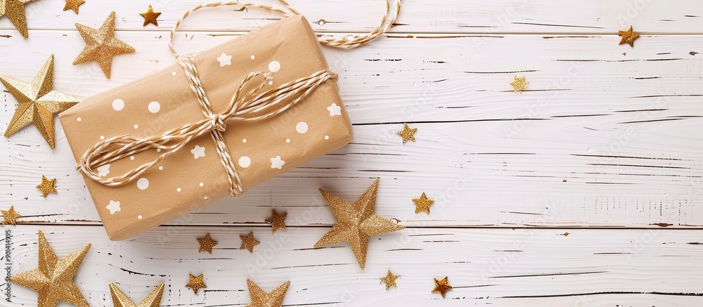 Poster gift box with star shaped decorations on a white wooden table background with ample copy space image