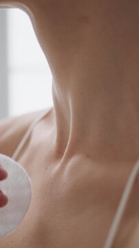 Woman hand rubbing neck lotion home vertical closeup. Unknown girl using pad