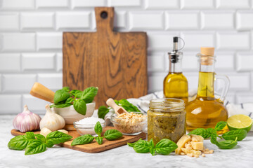 Pesto. Italian basil pesto sauce on a textured wooden background. Ingredient for pesto sauce: fresh basil, pine nuts, Parmesan cheese and olive oil. Space for text.Copy space.