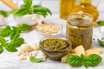 Pesto. Italian basil pesto sauce on a textured wooden background. Ingredient for pesto sauce: fresh basil, pine nuts, Parmesan cheese and olive oil. Space for text.Copy space.
