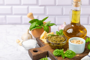 Pesto. Italian basil pesto sauce on a textured wooden background. Ingredient for pesto sauce: fresh basil, pine nuts, Parmesan cheese and olive oil. Space for text.Copy space.