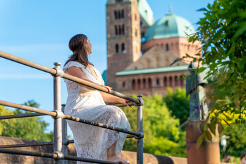 woman in a white dress is sitting on a railing overlooking a city