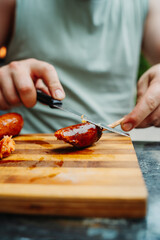 Close up of man hands cutting bbq sausage with knife